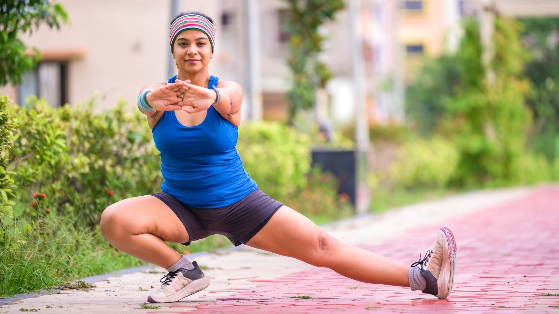 woman in shorts stretches into a side lunge while training outside 