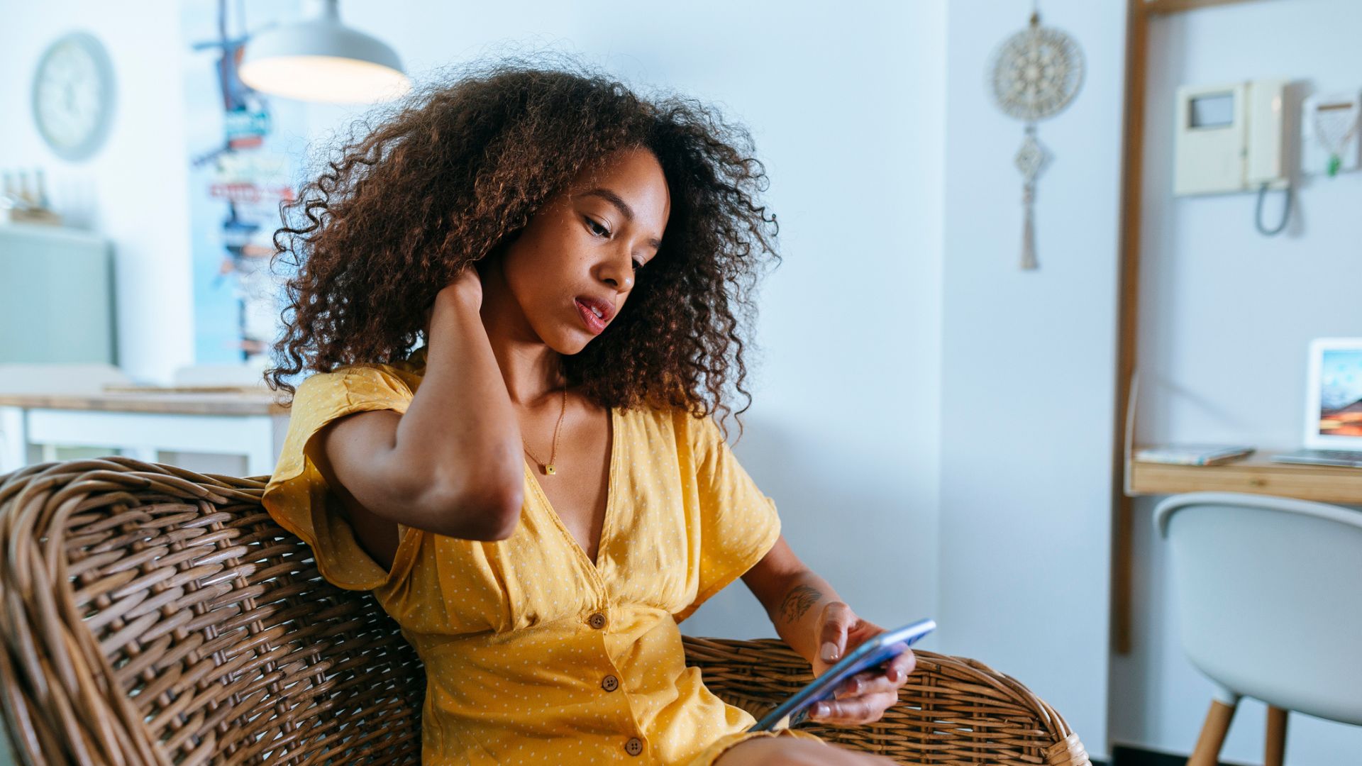 woman rubs neck while scrolling on phone 