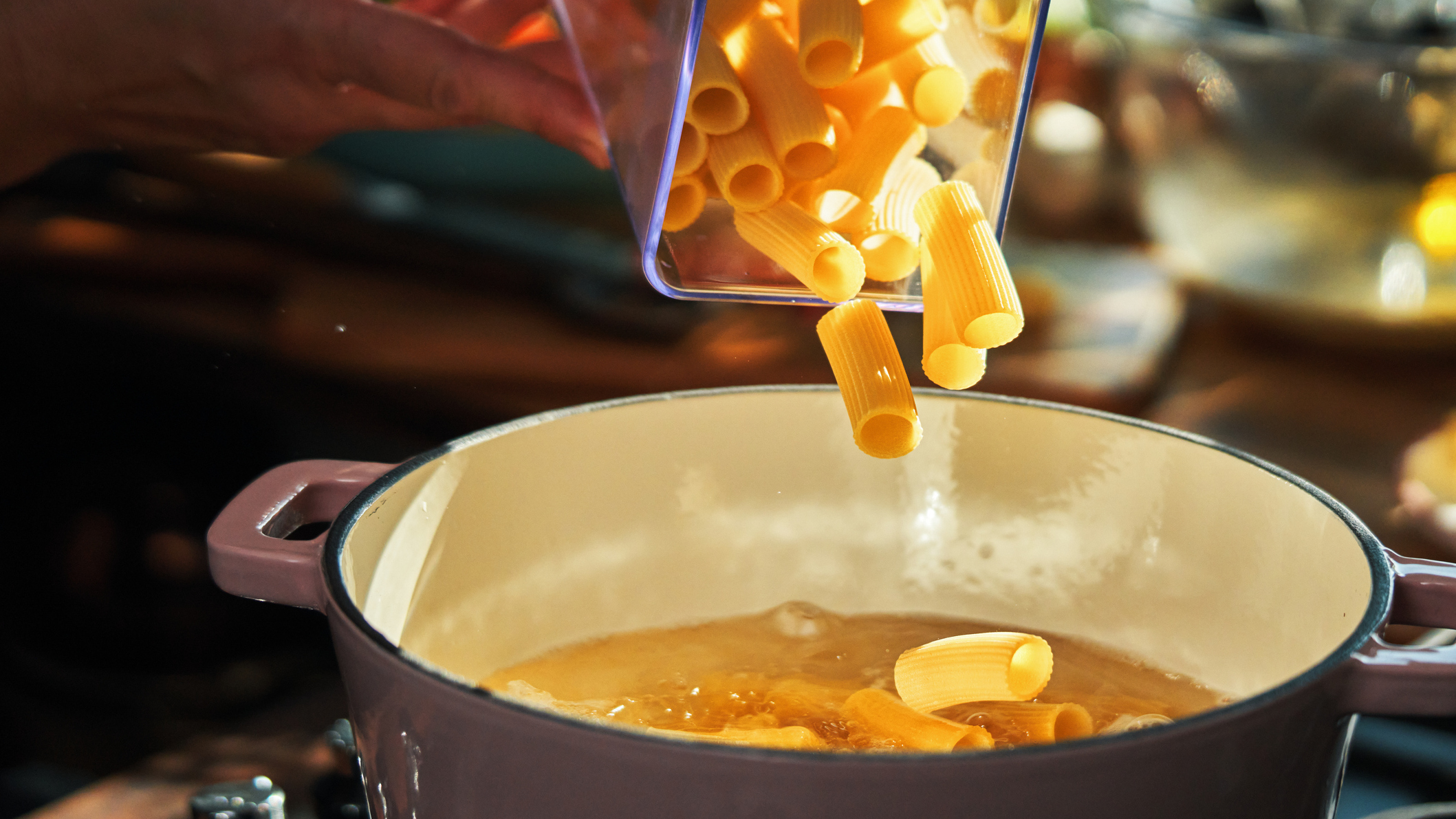 Glass jar of pasta being poured into casserole dish
