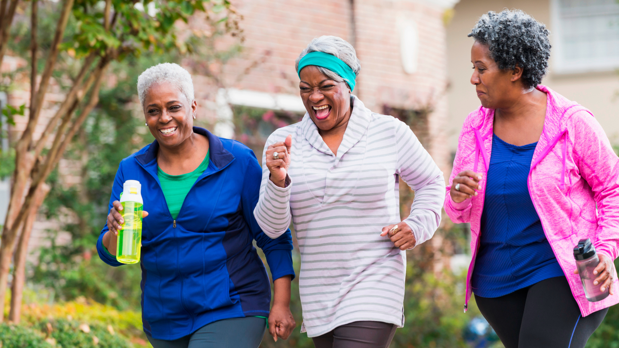 Three women in sportswear walking and smiling, two carry water bottles