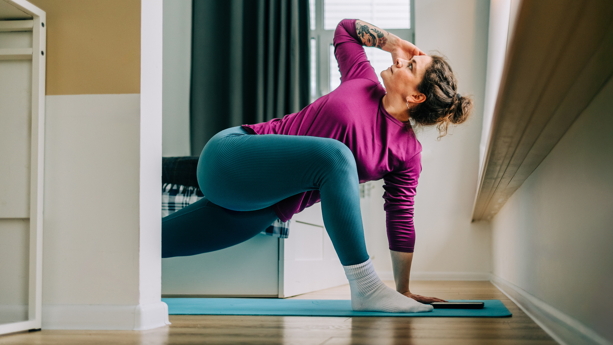 Woman at home practicing yoga. She is in low lunge with her torso twisted so she looks at the ceiling